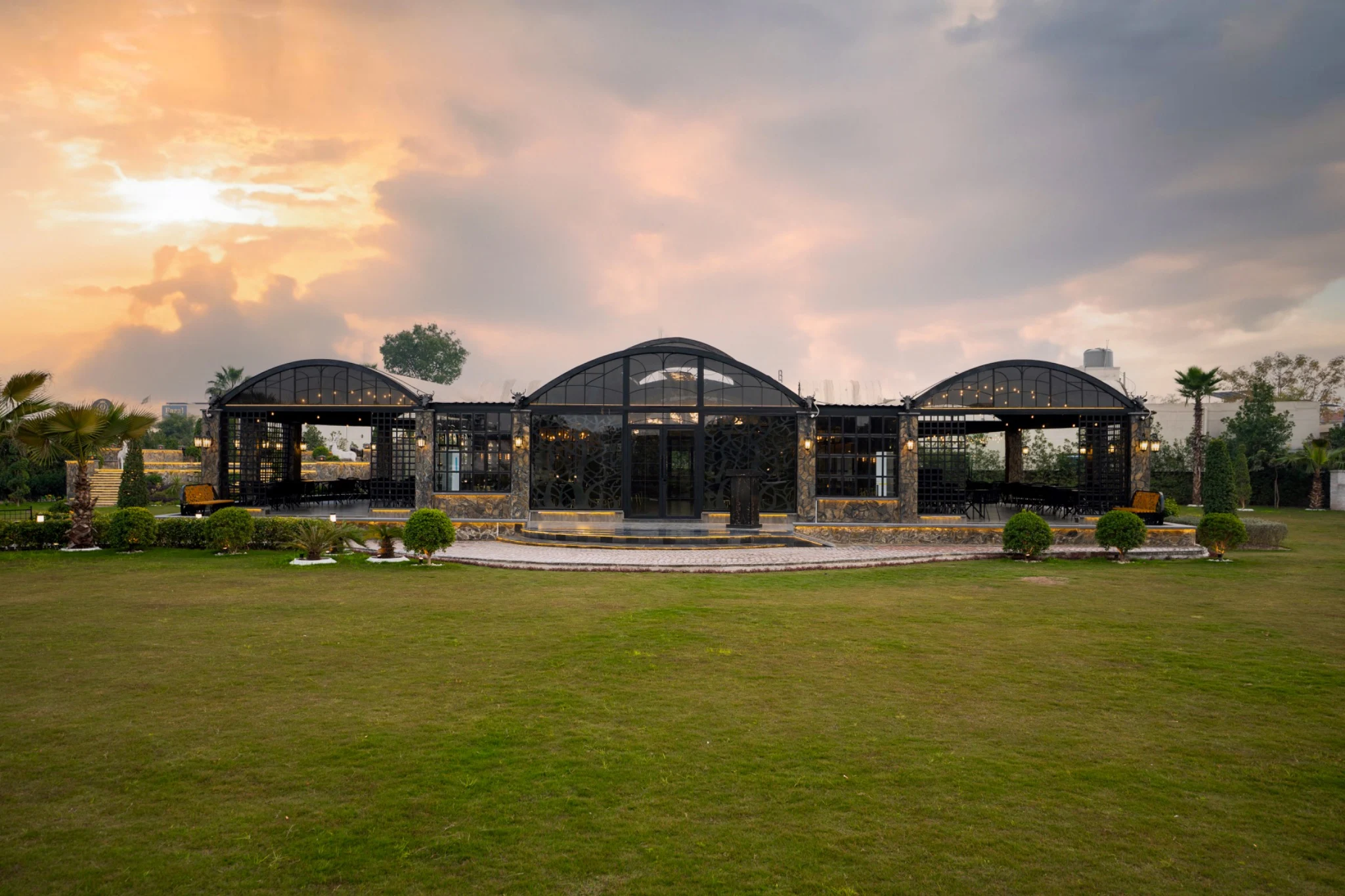 The glass pavilions opening onto the lawns beneath a golden Lahore sky