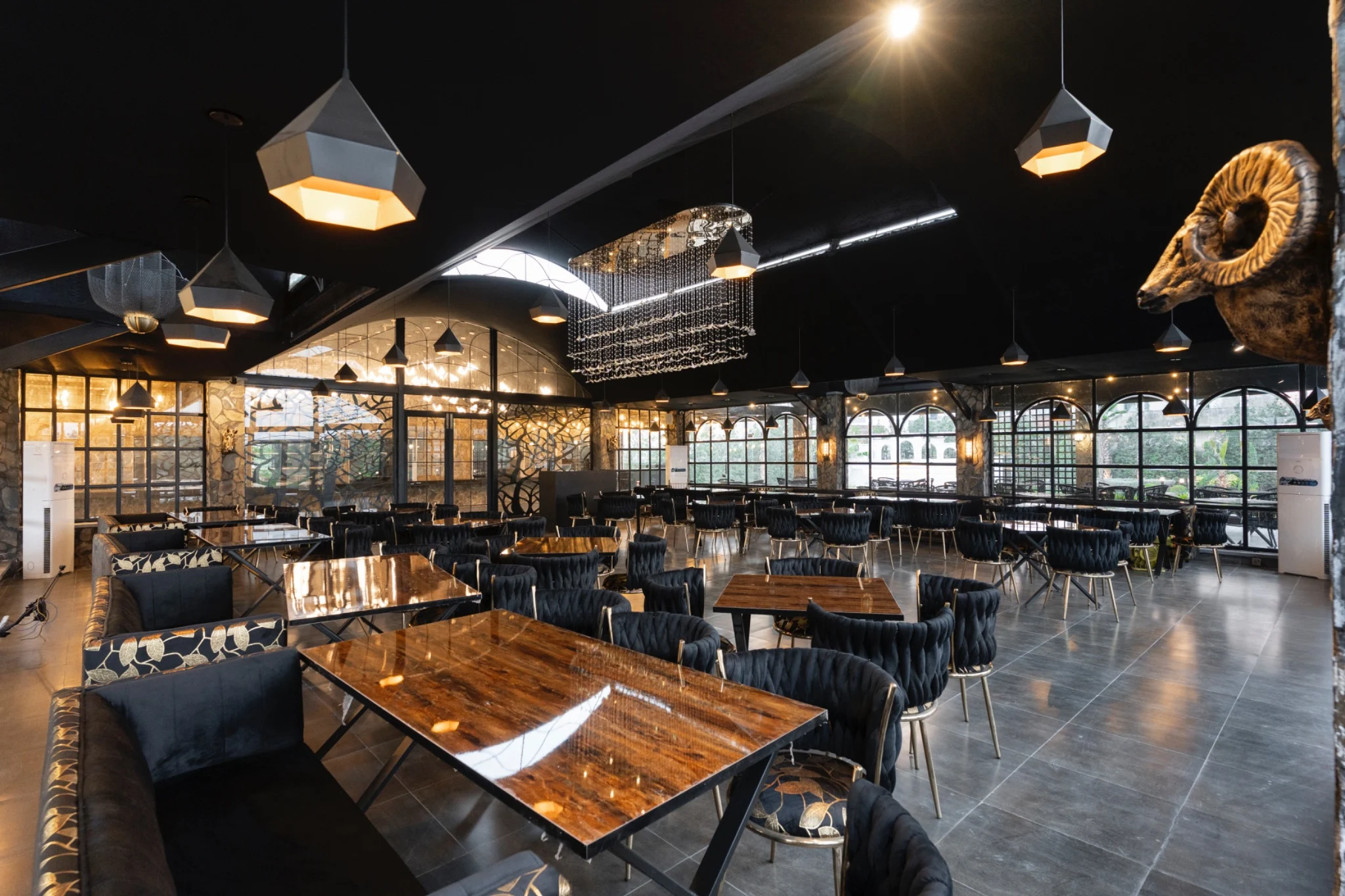 Warmly lit interior with timber tables and full-height glass walls